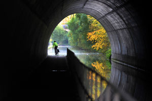 A cyclist makes his way through the tunnel along the Main Line Canal, Smethwick, as the autumn colours of the leaves reflect in the water