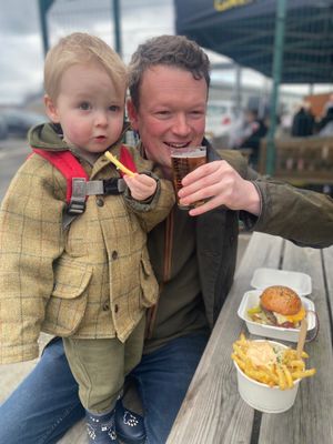 Dad Sam James (from Leominster) enjoying a beer, and son two-year-old Bertie tucking into the burger meal from The Beefy Boys. Picture: Ludlow Brewery