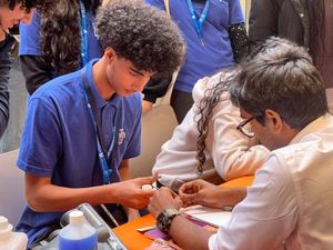 Young students practice suturing at a career stall ran by medicine professionals