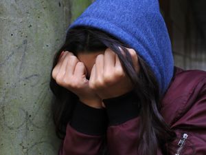 A teenager with her head in her hands