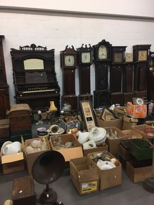 A collection of grandfather clocks and boxes of items from the home.