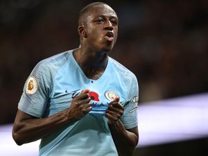 Benjamin Mendy holding the front of his Manchester City shirt while playing
