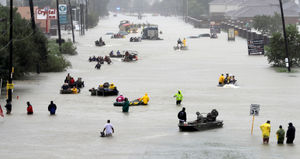 Rescue boats fill a flooded street as flood victims are evacuated as floodwaters from Tropical Storm Harvey rise on Monday