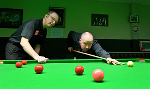Andrew Highfield watches on as reporter James Vukmirovic takes a shot at the black ball