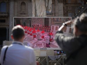 People in St Peter's Square watch a giant screen showing images of cardinals entering the conclave