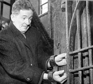 A local councillor demonstrates Much Wenlock's whipping post in 1966.