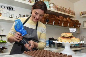 Miriam Gonzalez Durantez pipes a ganache filling into chocolates as she visits local cake shop Patisserie 13 in Newtown