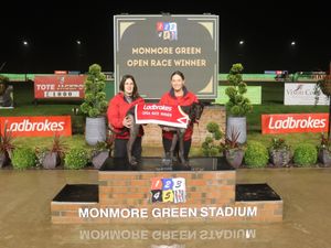 Newinn Deputy on the winners' podium with assistant trainer Jo Slater, left, and kennelhand Stacey Slater