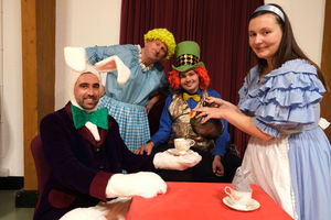 Guests at the Mad Hatter’s tea party – Floppy the White Rabbit Matthew Price, Graham Rimmer who plays Old Mother Wobbly, James Mitchell who plays the Mad Hatter and Alice played by Sasha Taylor. Image by Andy Compton