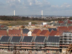 A view of homes being constructed with a bridge in the background