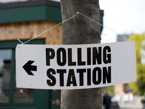 General view of a polling station sign attached to a tree.
