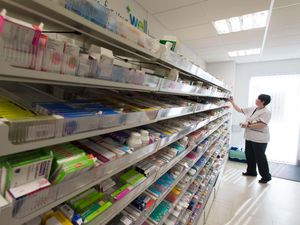 A female pharmacist picking an item from a shelf