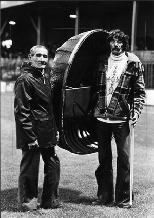 Fred Davies and his son Tom holding up a coracle on the Gay Meadow pitch