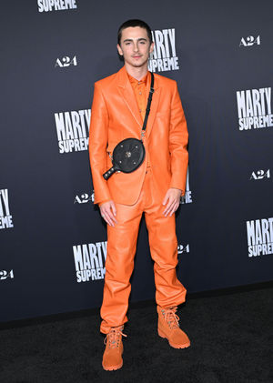 Timothee Chalamet wearing an orange suit and a table tennis bat shaped bag at the Los Angeles premiere of Marty Supreme in Beverly Hills