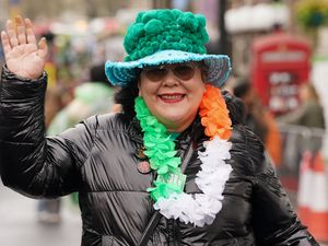 A woman in an extravagant green hat with a tricolour garland