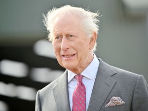King Charles III, wearing a grey suit, during a visit to Broighter Gold Farm, Limavady