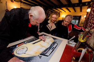 Former Jaguar test driver Norman Dewis signs Karen Kay's painting of partner Rob Keymer's Jaguar E-Type