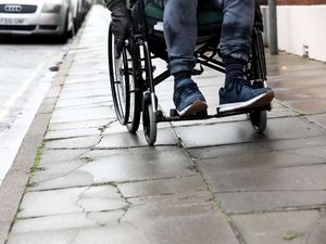 A man in a wheelchair pictured using it along an uneven path