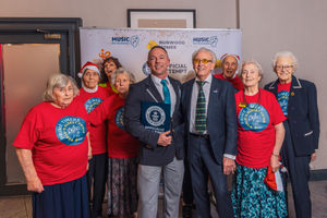 Members of the choir pose with Carl Saville (adjudicator for Guinness World Records) and Tony Christie