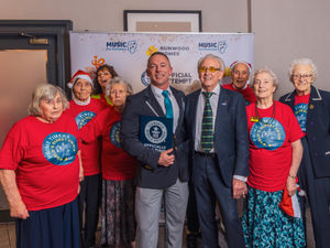 Members of the choir pose with Carl Saville (adjudicator for Guinness World Records) and Tony Christie