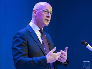 John Swinney speaking into a microphone