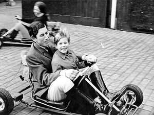 Prince Charles giving his five-year-old brother Prince Edward a ride on a go-kart in the grounds of Windsor Castle.  Princess Anne is seen driving a go-kart in the background.
