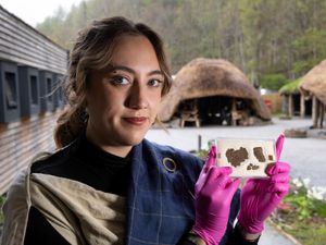 Woman holding textile fragments, at the Scottish Crannog Centre