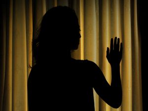 The silhouette of a woman next to closed curtains