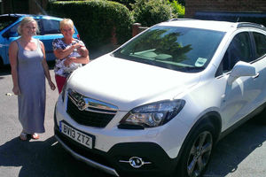 Mother Zoe Oliver by the car with grandmother Sue Oliver holding baby Joseph.