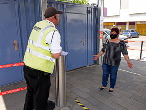 A customer is questioned by security before entering the market