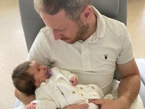Man cradling his newborn daughter