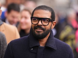 A head and shoulders shot of actor Noel Clarke, wearing large, dark-framed glasses