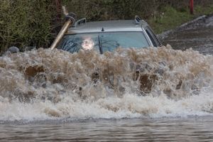 Image shows West Midlands dad Charlie Burns with his modified Peugeot 'submarine' driving through floodwater near Leicester.