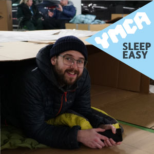 Young man lying in cardboard box to raise funds for ymca