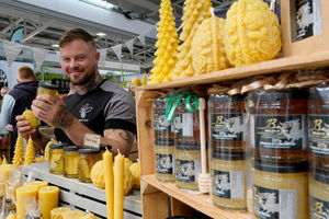 Tom Bottrill on the Welsh Honey stand in the food hall holding some of the chunk honey and a beeswax candle made near Builth Wells. Image by Andy Compton