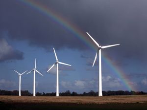 Wind turbines against a grey sky and rainbow