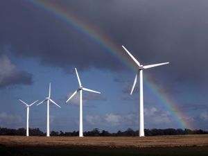 Wind turbines against a grey sky and rainbow