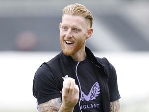 Ben Stokes, with a white ball in his hand, smiles