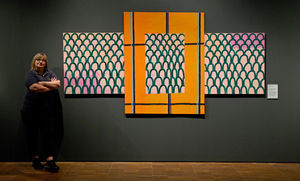 Visitor assistant Susan Chambers poses next to a piece called Invastion by Lubaina Himid from 1992