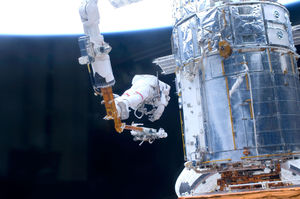 Astronaut John Grunsfeld, STS-125 mission specialist, positioned on a foot restraint on the end of Atlantis' remote manipulator system (RMS), participates in the mission's fifth and final session to refurbish and upgrade the Hubble Space Telescope in 2009