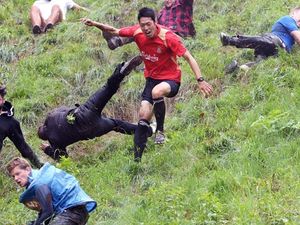 Supporting image for story: Drop everything and look at these glorious photos of people rolling down a hill after a wheel of cheese