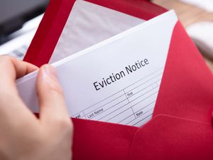 Close-up Of A Person's Hand Holding Eviction Notice In Red Envelope