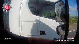 Shocking footage shows a lorry driver on the motorway in Gloucestershire with no hands on the wheel - as he rolls a cigarette.