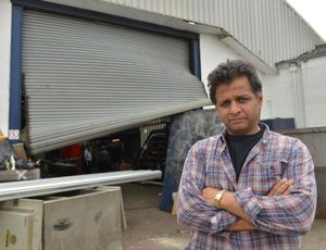 Paddy Kumar, from Branded Houswares, with one of the damaged roller shutters at his business
