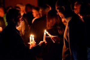 Attendees of the memorial service at The Black Country Living Museum light each others' candles.