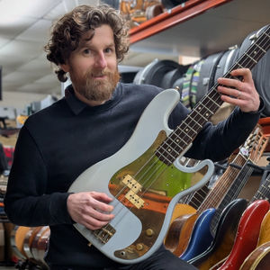 Auctioneer Luke Hobbs holding Horace Panter's bass guitar which he played in the hit song Ghost Town by The Specials.
