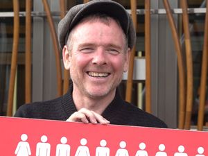 Stuart Murdoch holding a placard and smiling