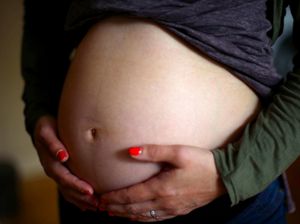 A pregnant woman holds her bump in London.