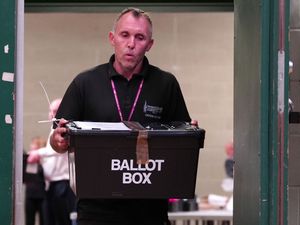 An election worker carrying a black ballot box at the Blackpool South by-election