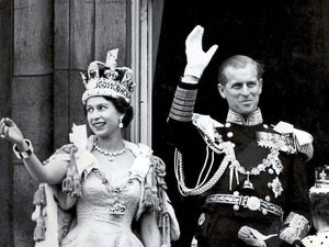 Queen Elizabeth II, wearing the Imperial State Crown, and the Duke of Edinburgh, in the uniform of Admiral of the Fleet, waving from the balcony of Buckingham Palace after the Queen's Coronation. 